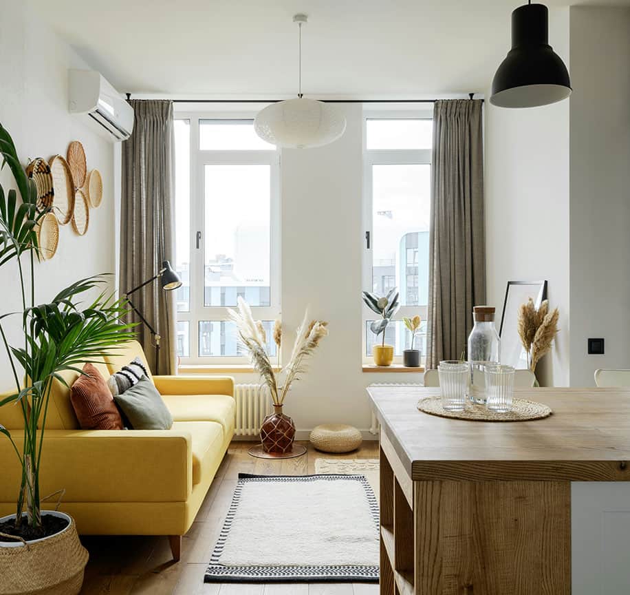 Bright living room with yellow sofa, large windows, and stylish decor.