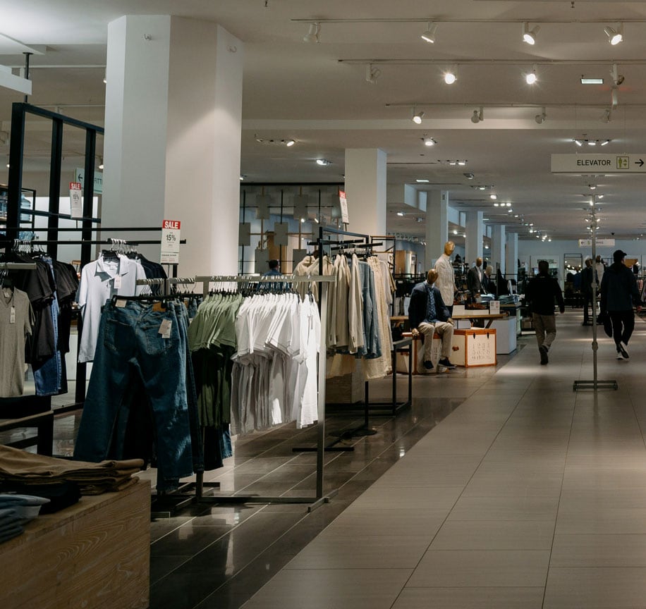 Clean retail store interior with clothing displays and shoppers.